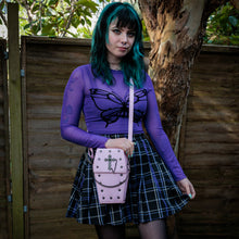 Load image into Gallery viewer, GothX Pastel Pink Mini Coffin Vegan Cross Body Bag being held up by an alternative goth model. The bag is facing forward to highlight the cross studs, cross &amp; chain centrepiece, detachable chain and detachable adjustable shoulder strap.
