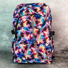 Load image into Gallery viewer, The planets solar system vegan backpack on a grey velvet background. The bag is facing forward to highlight the two zip front pockets, detachable silver chain, side pockets and multicoloured space front print.
