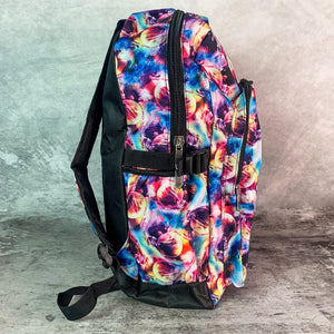 The planets solar system vegan backpack on a grey velvet background. The bag is facing right to highlight the two zip front pockets, main zip compartment, side pockets, padded adjustable shoulder straps and multicoloured space front print.