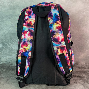 The planets solar system vegan backpack on a grey velvet background. The bag is facing away to highlight the padded adjustable shoulder straps with the multicoloured space print, plain black back, side pockets and top handle.
