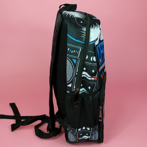 The retro black 80s stereo vegan backpack on a pink background. The bag is facing right to highlight the 80s stereo boombox front print, main zip compartment, two side pockets, top handle and padded adjustable shoulder straps.