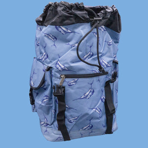 The Blue Swordfish Vegan backpack on a blue studio background. A pastel blue backpack with black buckle and strap detailing with swordfish printed all over. The bag is facing forward with the main compartment open to highlight the side buckle pockets, drawstring and buckle close and black piping detailing.