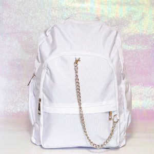 The white nylon vegan backpack with chain on an iridescent background. The bag is facing forward to highlight the two front zip pockets, two side pockets, double zip main compartment, top handle and detachable silver chain.