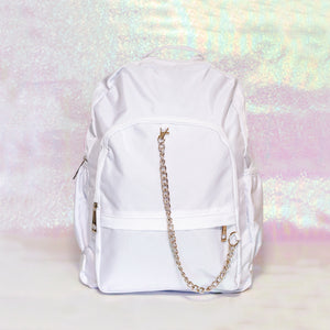 The white nylon vegan backpack with chain on an iridescent background. The bag is facing forward to highlight the two front zip pockets, two side pockets, double zip main compartment, top handle and detachable silver chain.