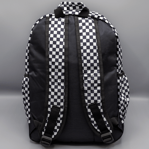 The White Checkerboard Backpack sat on a grey background. The vegan friendly bag features an all over mini black and white check print with black trim along the silver zips. The bag is facing away from camera to highlight the plain black back, the top handle and adjustable padded shoulder straps.